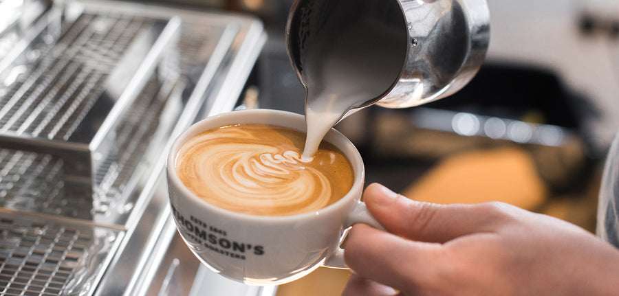 Latte art being poured into a Thomson's cup