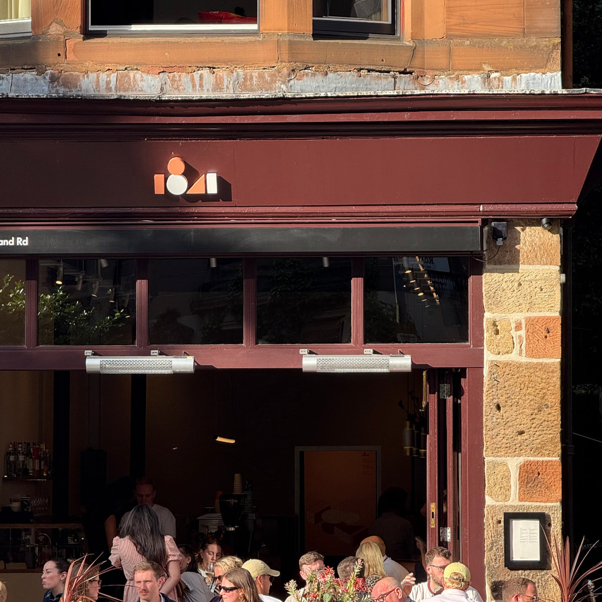 People sitting outside a building with a sign that reads '1841'.