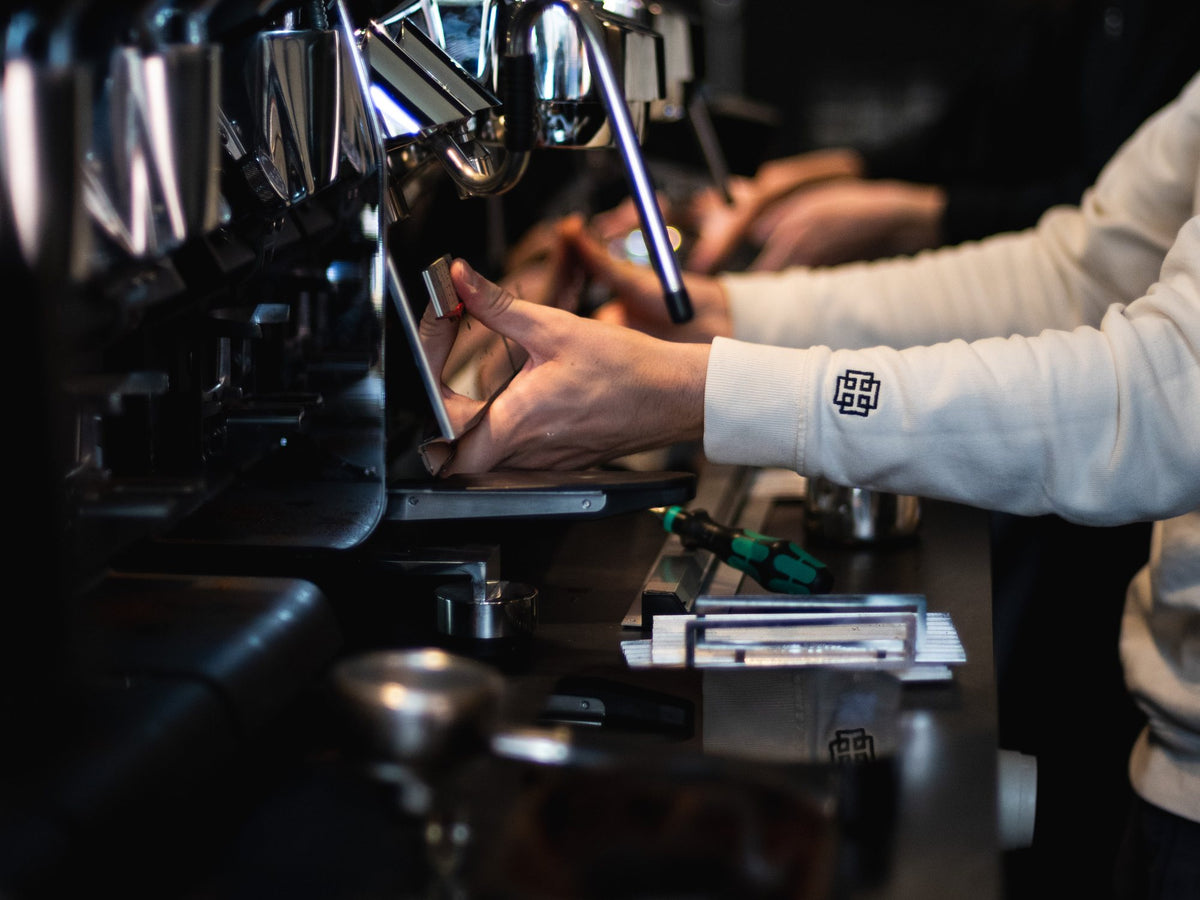A barista's hands working the espresso machine at Thomson's